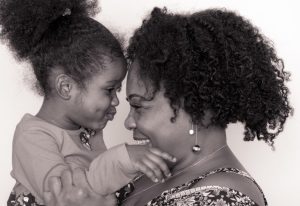 Mother and young daughter facing each other and smiling